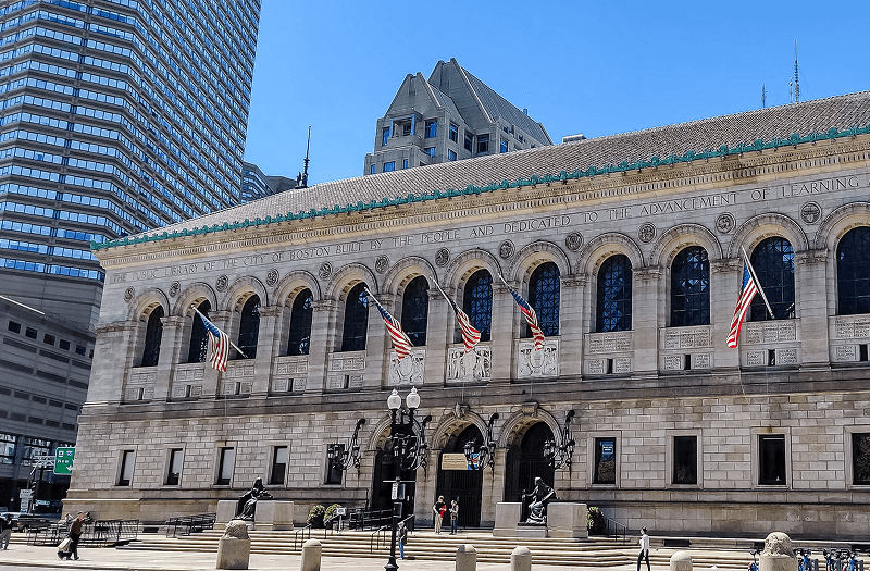 The main entrance and façade of the Boston Public Library with high-rise buildings visible in the background.