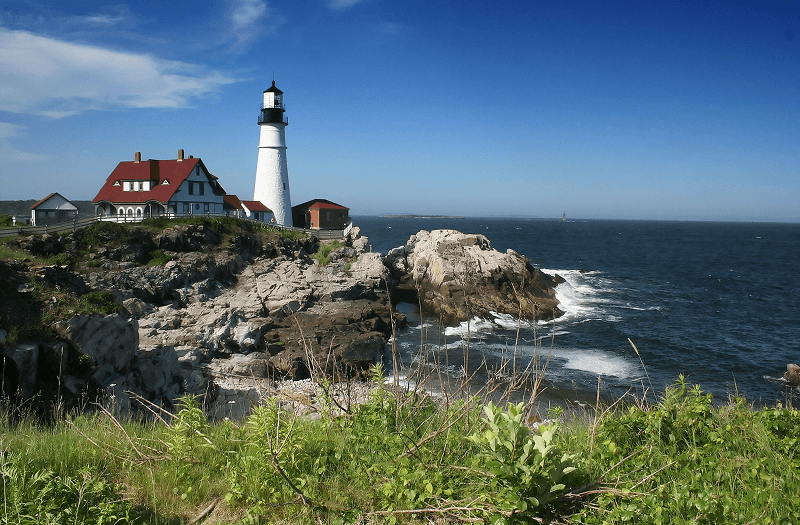 A lighthouse on a rocky New England cliff overlooking the ocean.