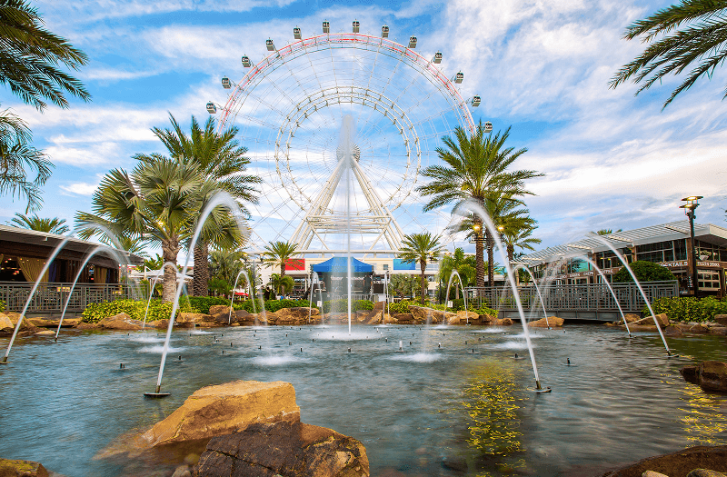 A water fountain in front of a colorful Ferris wheel in the Orlando area.