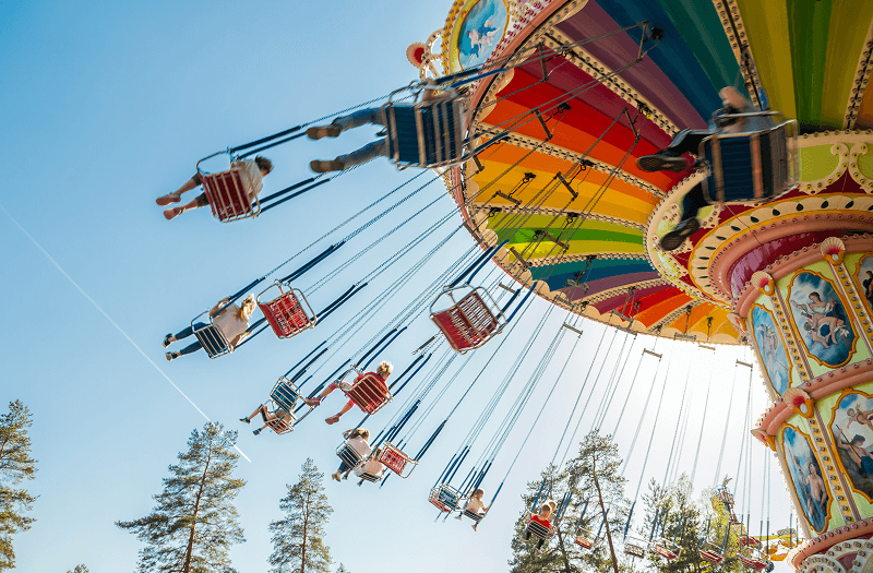 A colorful flying chair ride with people in the high-flying seats.