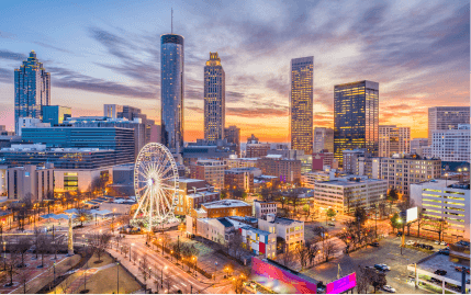 The Downtown Atlanta skyline at sunset, with many tall buildings, SkyView Atlanta, and the Centennial Olympic Park.