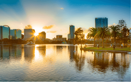 View of the downtown Orlando skyline and people enjoying Lake Eola at sunset.