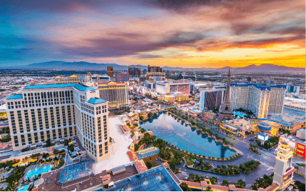 Aerial view of the Las Vegas Strip with the Fountains of Bellagio, Eiffel Tower Viewing Deck, and High Roller during a beautiful sunset.
