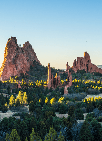 A striking rock formation rises in the center of a grassy field in Colorado, showcasing the natural landscape.