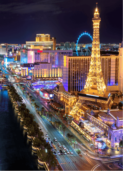 Aerial view of the Las Vegas Strip and Eiffel Tower Viewing Deck at night, with everything illuminated by beautiful lights.