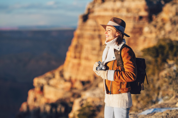 Person looking at the horizon, holding a camera, with rocky mountain in the background