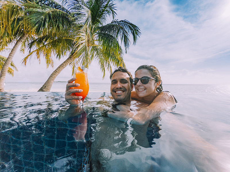 Young adult couple doing a selfie in the swimming pool in a paradisiac island.