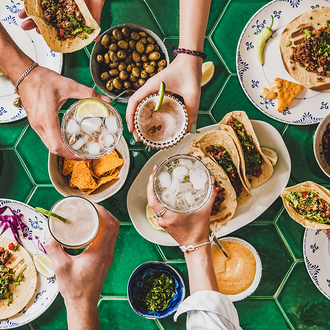A group of friends joyfully toasting with drinks and sharing food at a festive gathering.