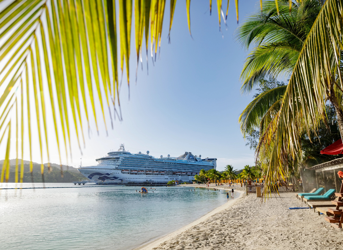 A cruise ship docked at an island shore on a bright sunny day.
