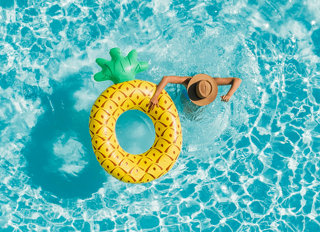 View from above of a person in the water wearing a hat, holding a life preserver