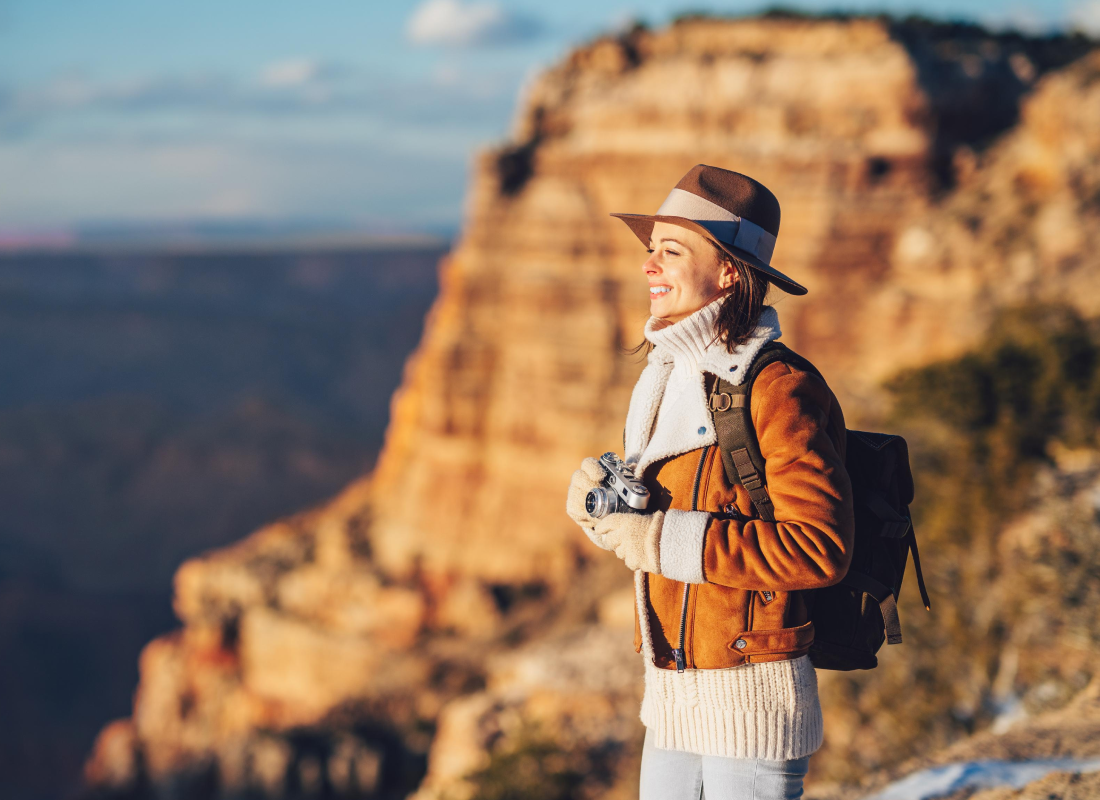 Person looking at the horizon, holding a camera, with rocky mountain in the background