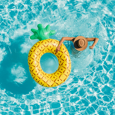 View from above of a person in the water wearing a hat, holding a life preserver