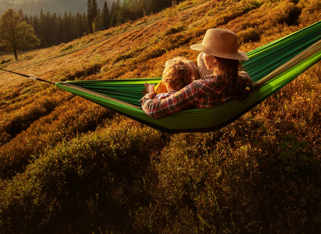 A woman and child relax together in a cozy hammock, enjoying a peaceful moment outdoors.  