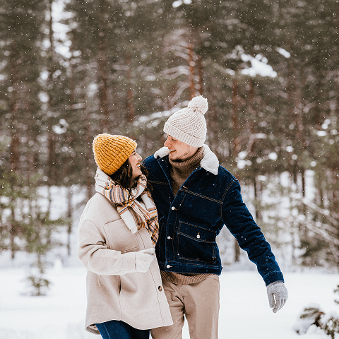 A couple enjoying a snowy day together in the forest.