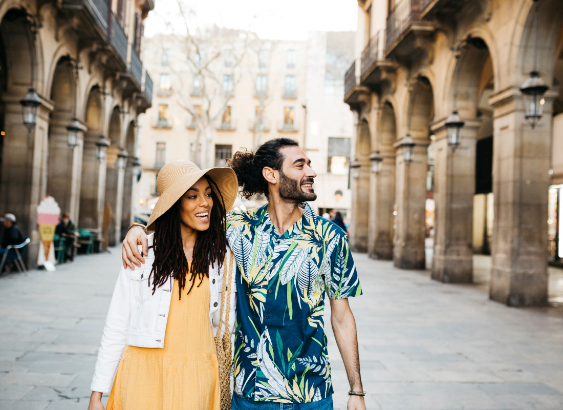 A couple enjoying a sunny day in Barcelona, Spain, with historic architecture in the background.