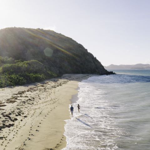 A couple walking leisurely on a beach on a sunny day.