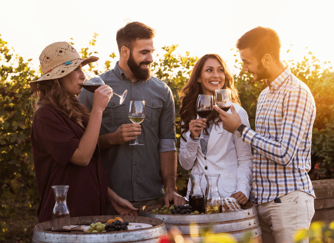 A group of people enjoying wine at a winery on a beautiful afternoon.