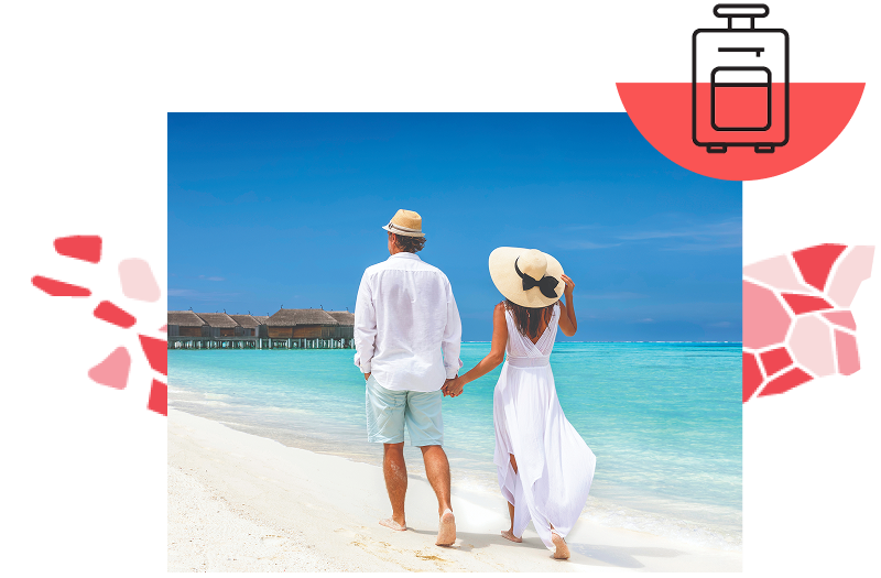A man and woman wearing hats and walking barefoot down a white sand beach with no clouds in the sky.