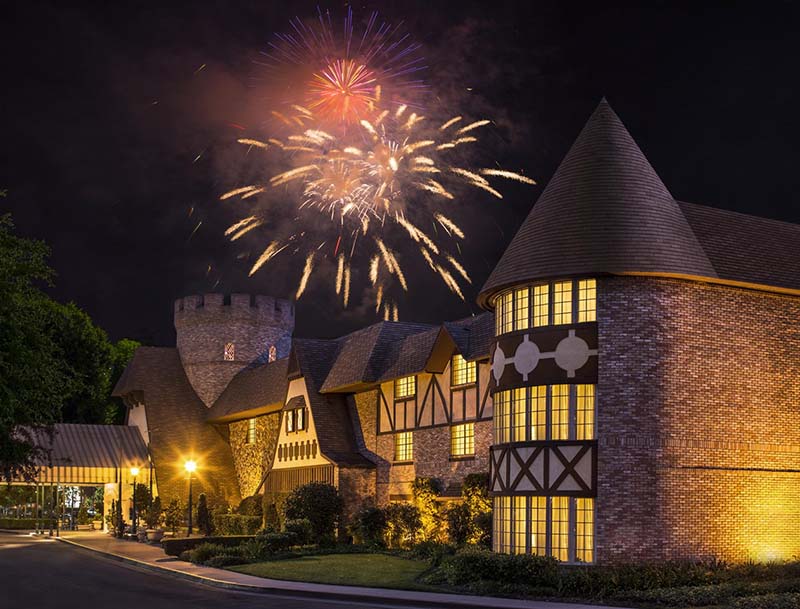 The hotel's brightly illuminated facade and entrance, with colorful fireworks adorning the night sky above.