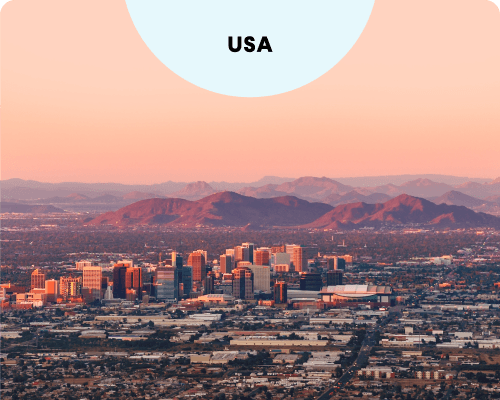 The Phoenix, Arizona skyline at sunset, featuring downtown buildings against a backdrop of purple mountains and a warm orange sky.