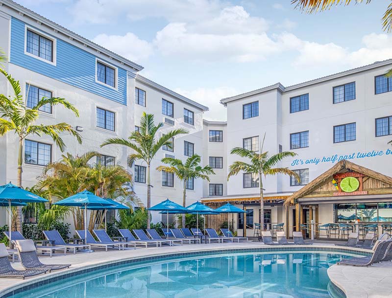 A view of the hotel's serene pool surrounded by lounge chairs, umbrellas, and tropical landscaping.