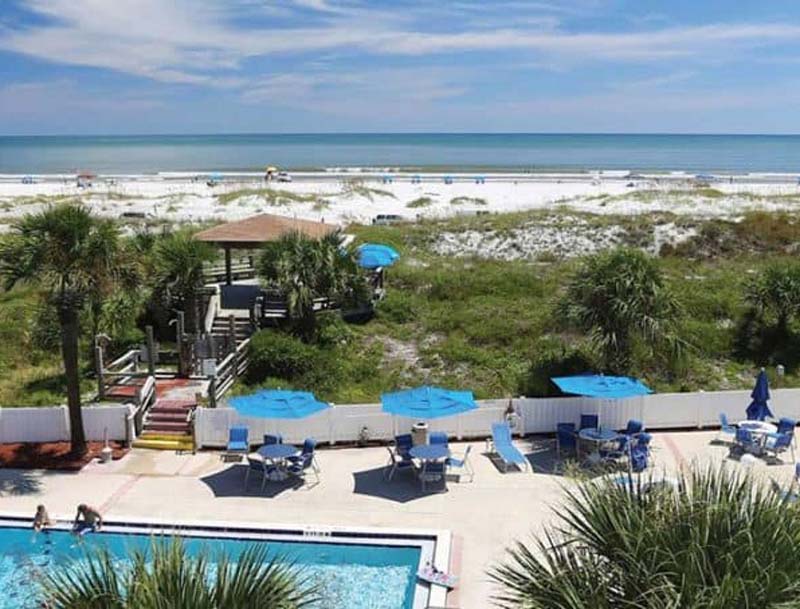 A scenic view of the hotel's pool deck and boardwalk leading to the sandy beach.