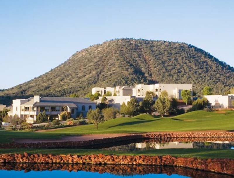 A view of the resort nestled between a lush green golf course and a mountain ridge in the distance.