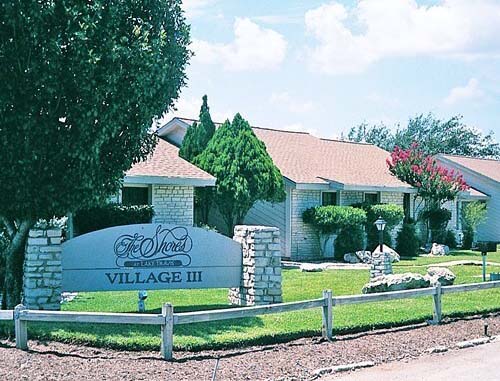 The entrance sign and lushly-landscaped buildings at The Shores At Lake Travis resort. 