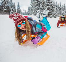 A smiling woman sliding downhill on a snow board