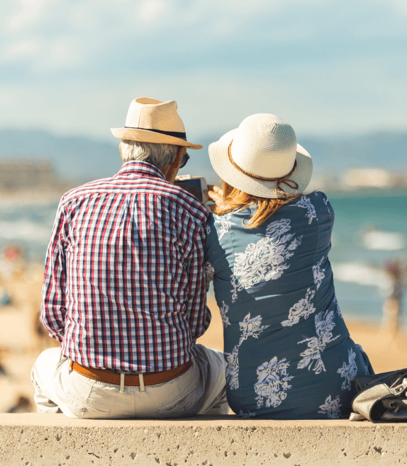 An older couple taking pictures of the shore with their phone.