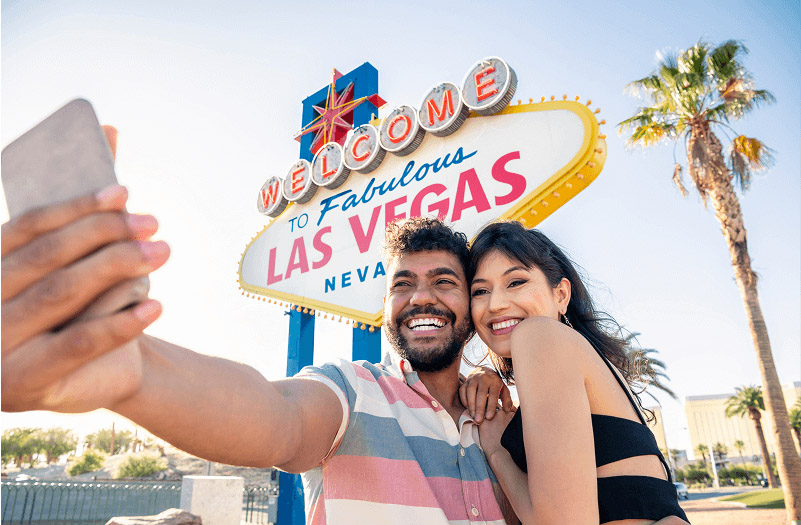 A couple taking a selfie in front of the Las Vegas sign.