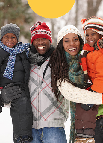 Two adults and two children smiling with snowy background