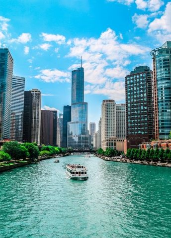The Chicago River meanders past the skyline, featuring iconic skyscrapers under a sunny, clear sky.