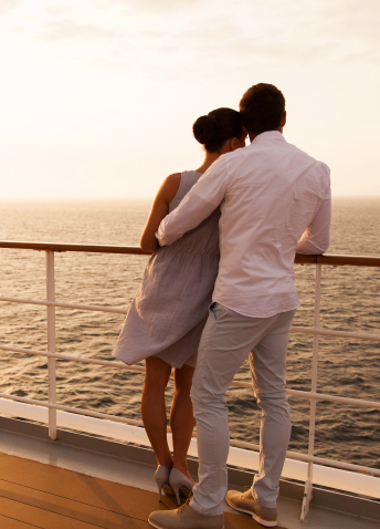 Two people hugging watching the sea from the deck of a cruise ship