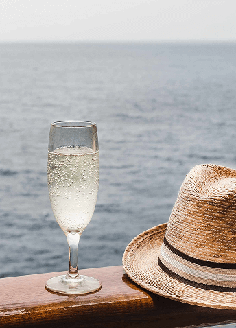 Cup with drink and hat on a railing, with the sea in the background