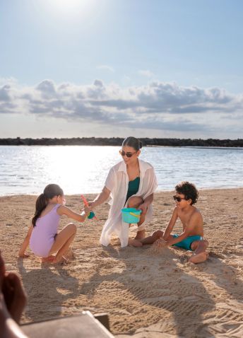 A woman and children building sand castles at the beach.
