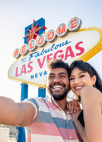 A couple happily taking a selfie in front of the infamous Welcome to Las Vegas sign.
