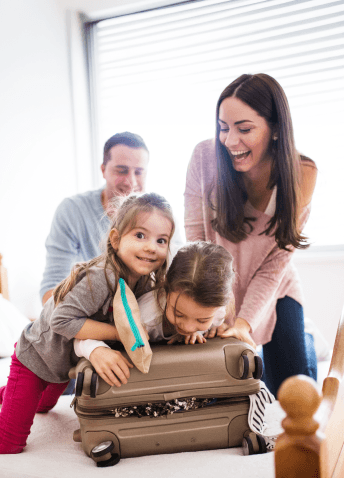 Happy family leaning on a packed suitcase on a bed as they prepare for a vacation.