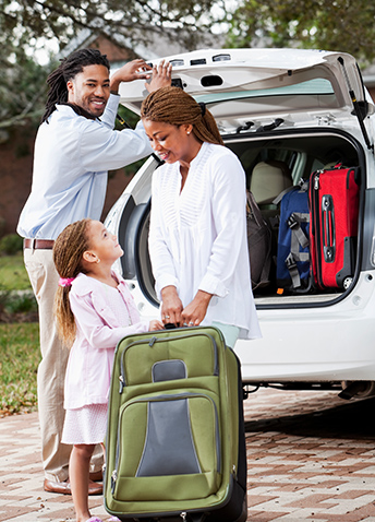 A Black family packing up their car for a trip